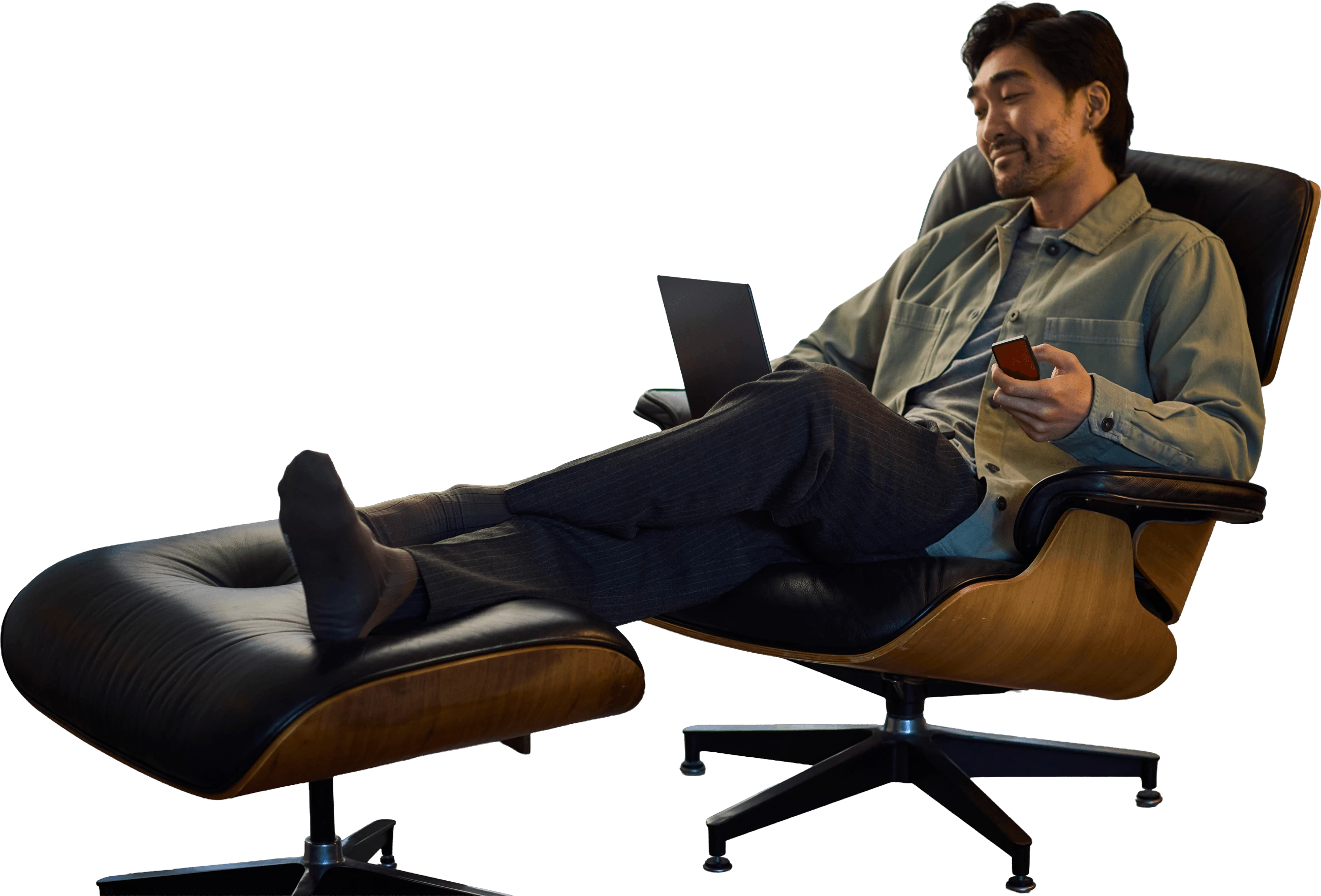 Homme souriant assis dans un fauteuil avec un ordinateur portable et un smartphone, entouré de pièces Bitcoin illustrées.