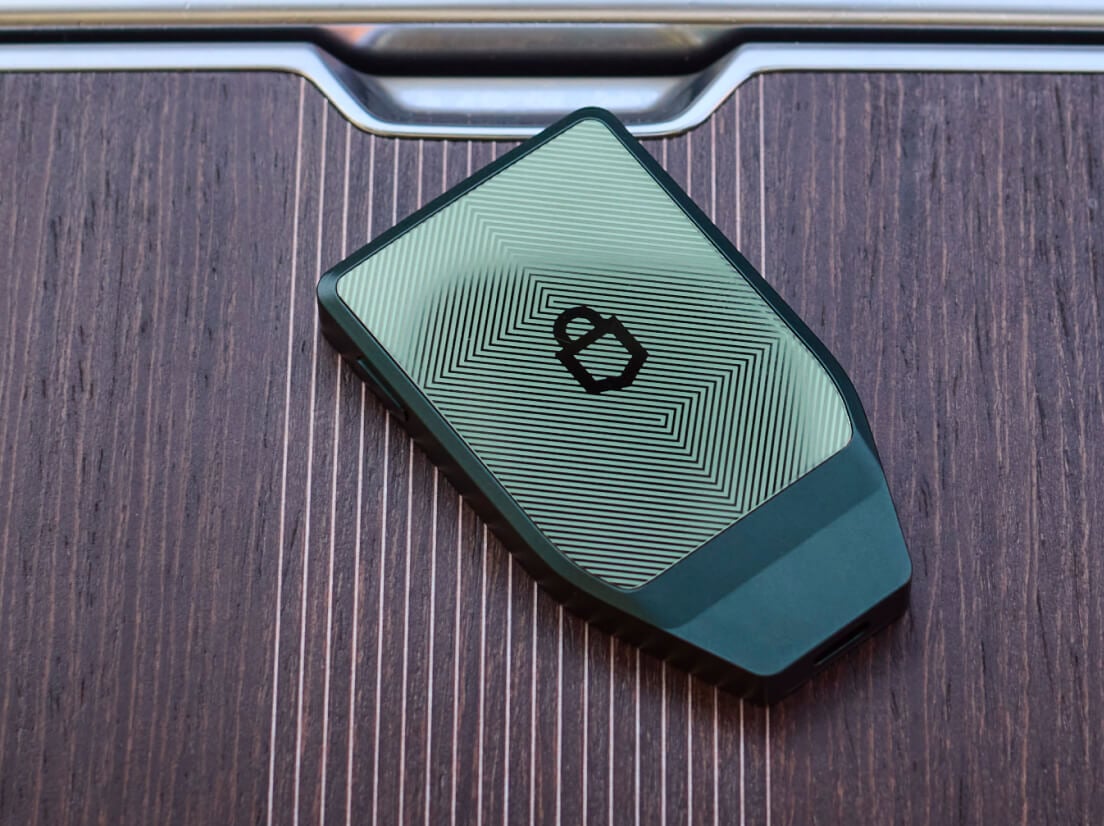 Un Trezor Safe 7 Vert Obsidienne posé sur une surface en bois sombre.